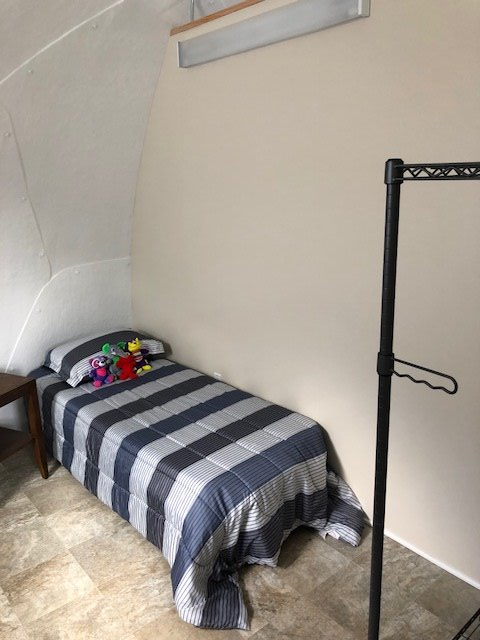 bed with stuffed animals inside tiny house or safety shelter from InterShelter Inc.